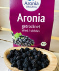 dried aronia original berries on wooden spoon