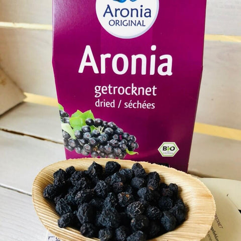 dried aronia original berries on wooden spoon