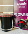 aronia berry juice in glass in front of aronia original 3 L aronia juice box